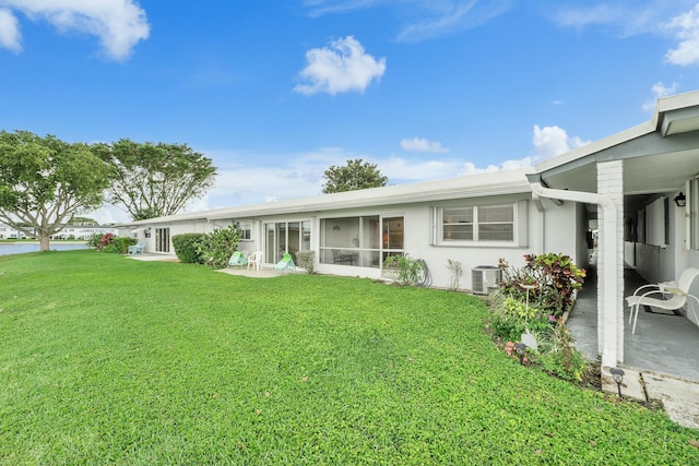 rear view of property with cooling unit and a lawn