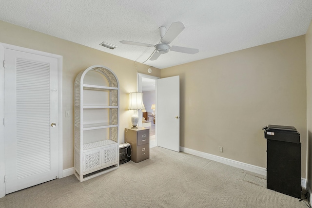 unfurnished bedroom featuring ceiling fan, light carpet, and a textured ceiling