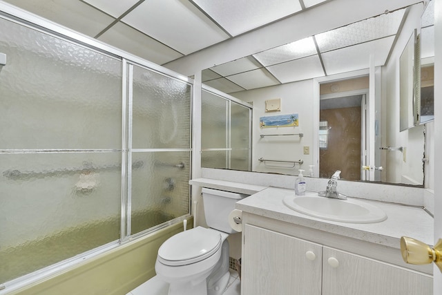 full bathroom with bath / shower combo with glass door, vanity, toilet, and a drop ceiling