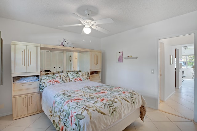 tiled bedroom with ceiling fan and a textured ceiling