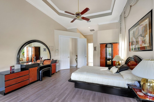 bedroom featuring a raised ceiling, ornamental molding, high vaulted ceiling, and light hardwood / wood-style flooring