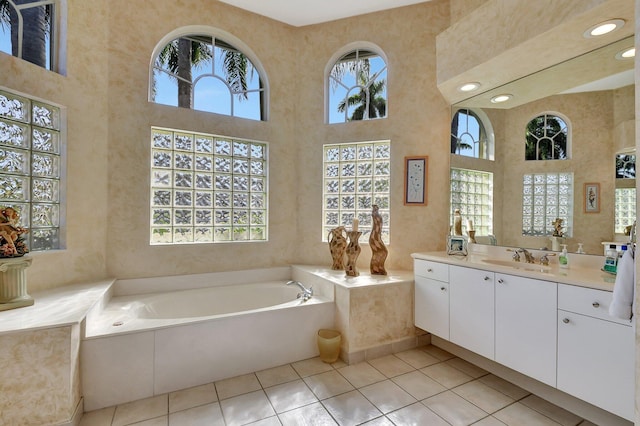 bathroom featuring tile patterned flooring, vanity, a high ceiling, and a tub to relax in