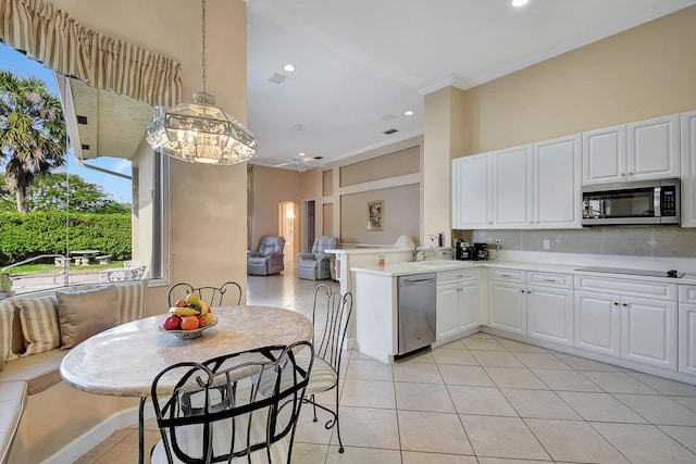 kitchen with light tile patterned floors, appliances with stainless steel finishes, white cabinetry, hanging light fixtures, and kitchen peninsula