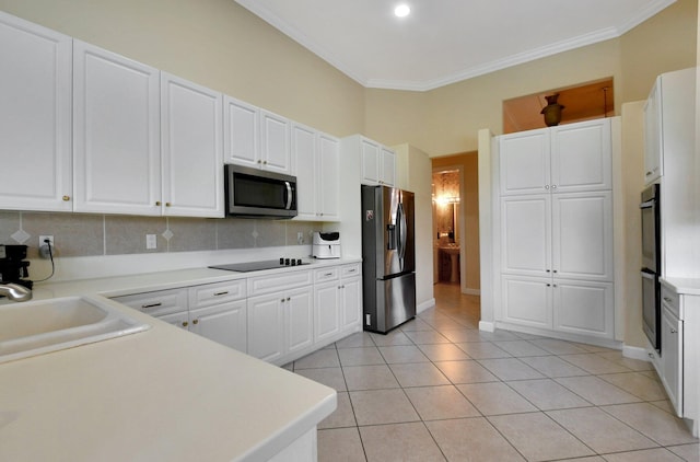 kitchen featuring appliances with stainless steel finishes, white cabinets, decorative backsplash, light tile patterned floors, and crown molding