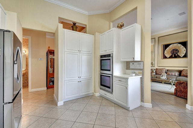 kitchen featuring light tile patterned flooring, ornamental molding, stainless steel appliances, and white cabinets