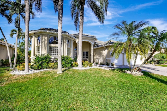 mediterranean / spanish-style house with a garage and a front lawn