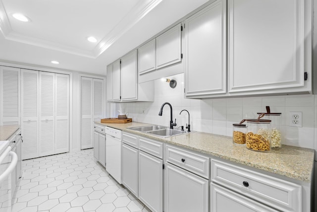 kitchen with white cabinetry, a tray ceiling, dishwasher, and sink