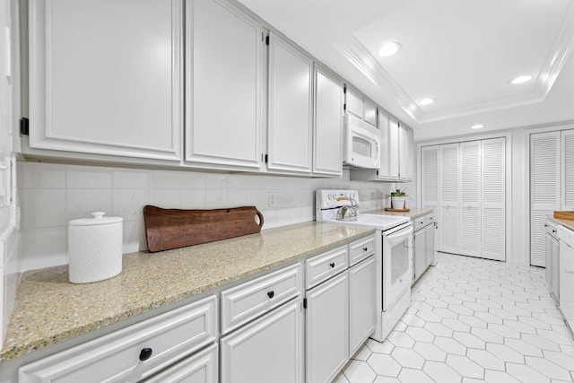 kitchen with white cabinetry, ornamental molding, white appliances, and a tray ceiling