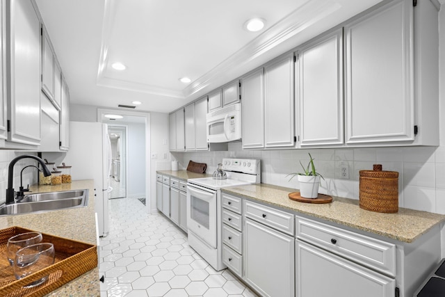 kitchen with sink, backsplash, light tile patterned floors, a tray ceiling, and white appliances