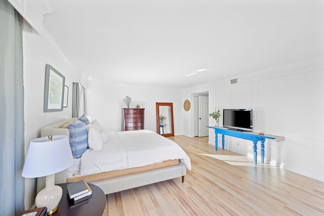 bedroom with crown molding and light wood-type flooring