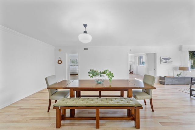 dining area featuring crown molding and light hardwood / wood-style flooring