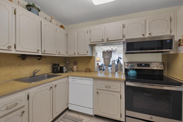 kitchen featuring stainless steel appliances, sink, light tile patterned floors, and white cabinets
