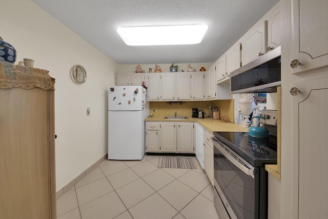 kitchen with light tile patterned floors, sink, appliances with stainless steel finishes, white cabinetry, and backsplash