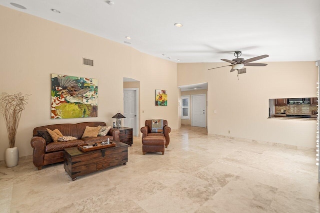 living room with ceiling fan and a high ceiling