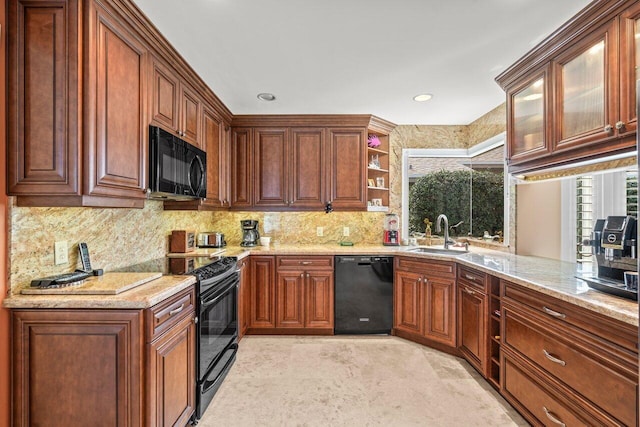 kitchen with light stone counters, sink, decorative backsplash, and black appliances