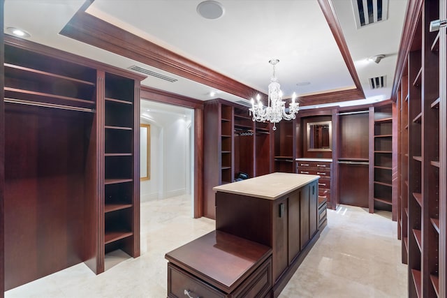 spacious closet with an inviting chandelier and a tray ceiling