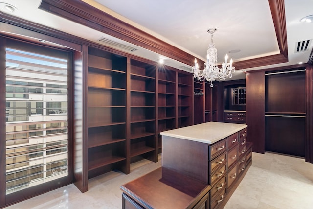 walk in closet featuring a tray ceiling and a chandelier