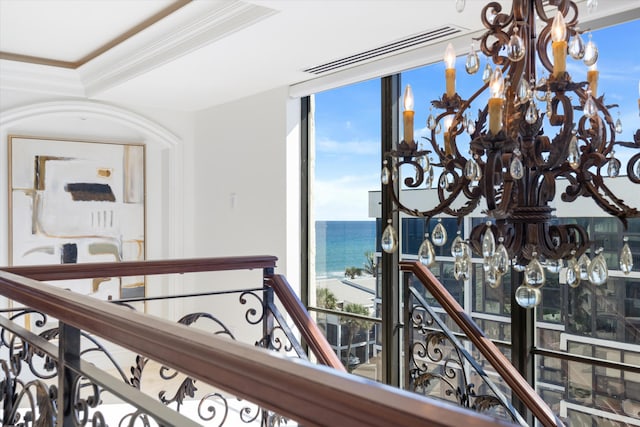 corridor with an inviting chandelier, crown molding, and a water view