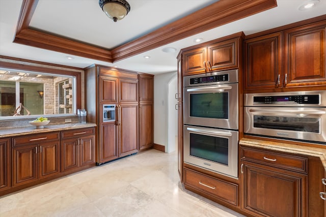 kitchen with crown molding, stainless steel double oven, and a raised ceiling