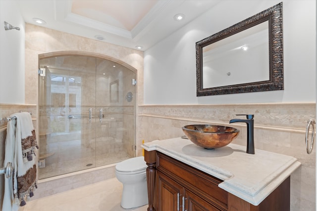 bathroom featuring crown molding, tile walls, vanity, a shower with shower door, and toilet