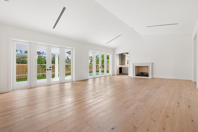 unfurnished living room featuring light wood-style floors, lofted ceiling, french doors, and a fireplace