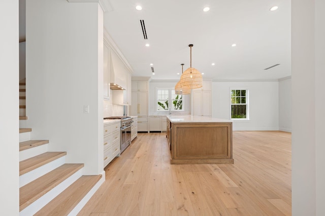 kitchen featuring recessed lighting, a kitchen island, light countertops, high end stainless steel range, and light wood-type flooring