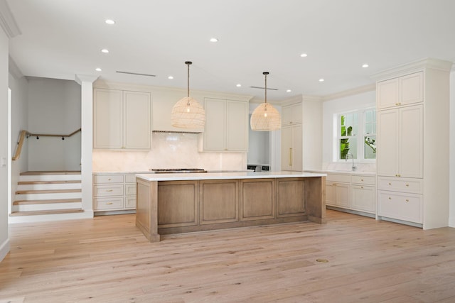 kitchen featuring light countertops, tasteful backsplash, a kitchen island, and light wood-style flooring