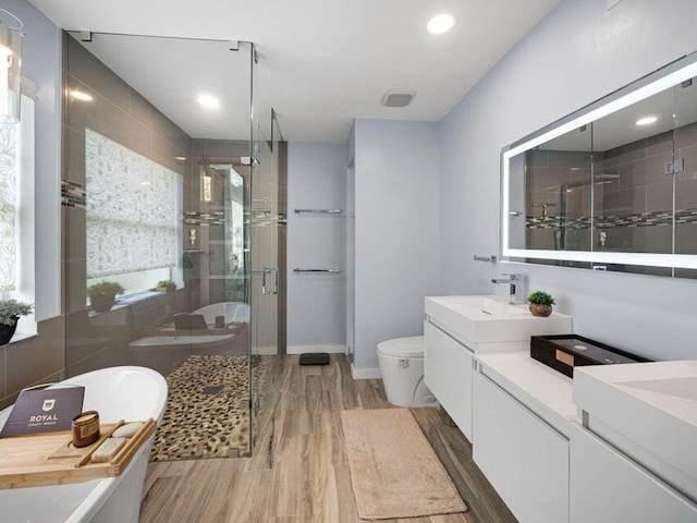 full bathroom with independent shower and bath, wood-type flooring, vanity, and toilet