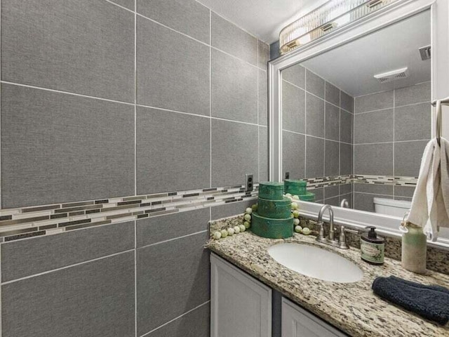 bathroom featuring vanity and tile walls