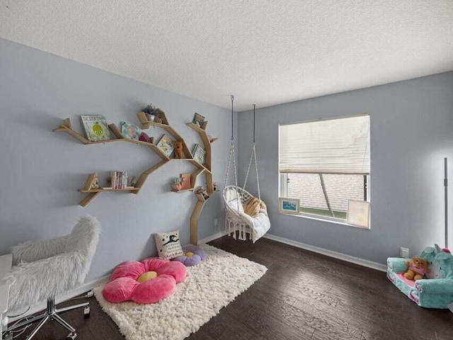 playroom featuring dark wood-type flooring and a textured ceiling