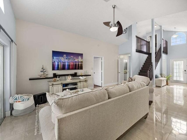 living room featuring ceiling fan, high vaulted ceiling, and a textured ceiling