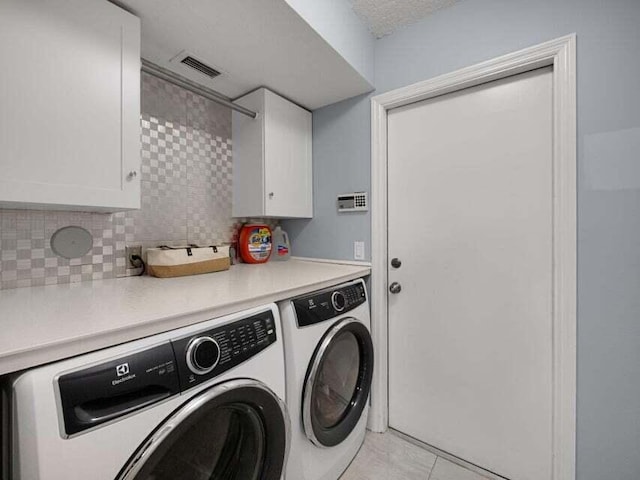 laundry area with cabinets, washing machine and dryer, light tile patterned floors, and a textured ceiling