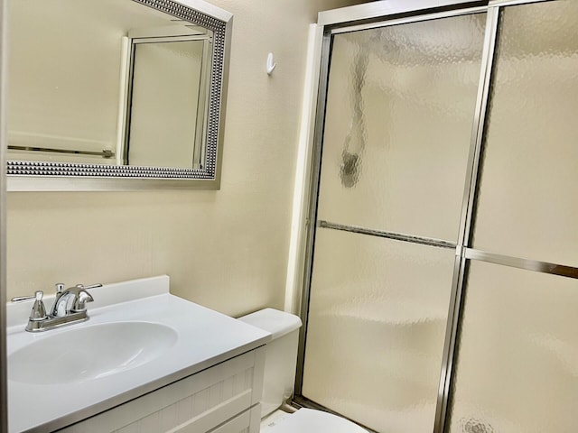 bathroom featuring vanity, toilet, and a shower with shower door