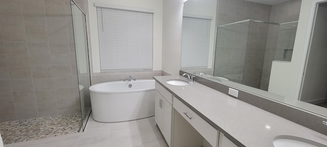 full bathroom with double vanity, a stall shower, tile patterned flooring, a freestanding bath, and a sink