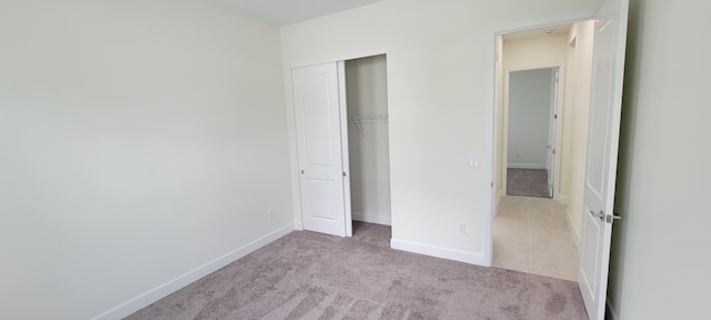 unfurnished bedroom featuring light carpet and a closet