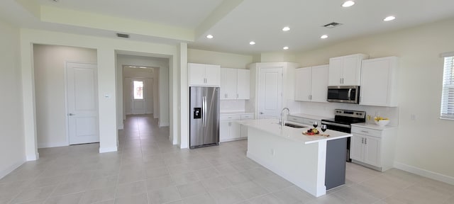 kitchen featuring sink, stainless steel appliances, tasteful backsplash, an island with sink, and white cabinets