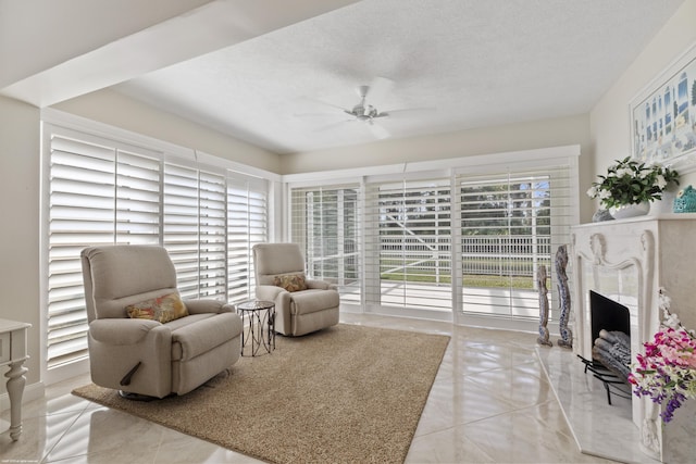 living area with ceiling fan, light tile patterned floors, and a textured ceiling