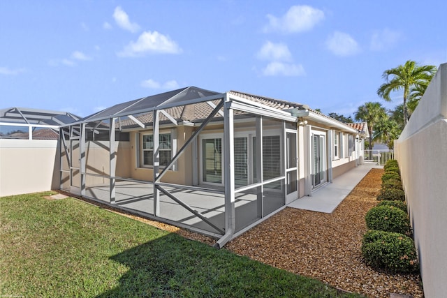 rear view of house featuring a lanai, a patio, and a lawn