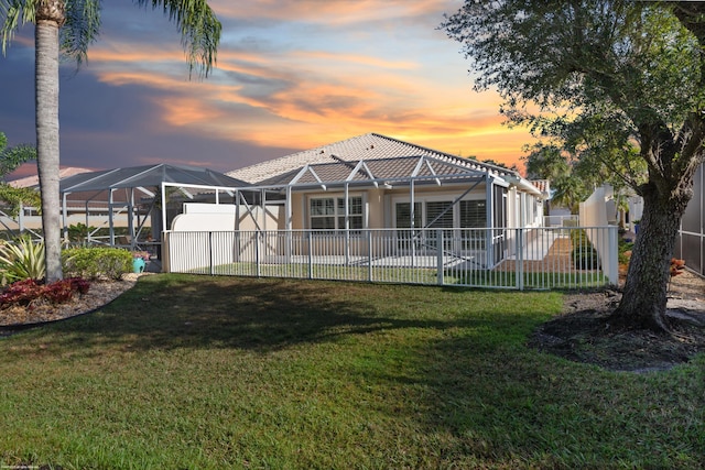 back house at dusk with a lanai and a yard