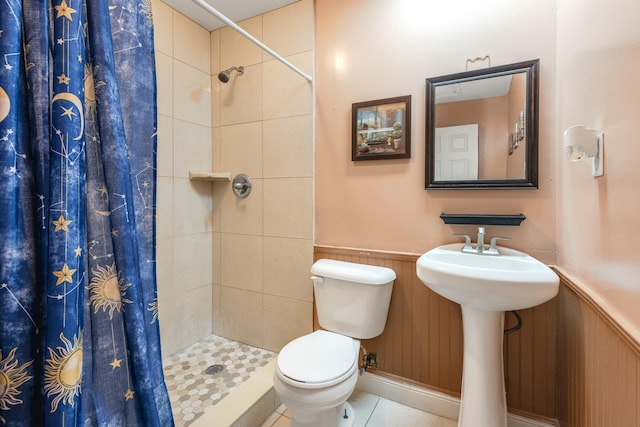 bathroom featuring wooden walls, sink, toilet, tile patterned floors, and a shower with shower curtain