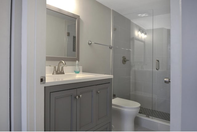 bathroom with walk in shower, vanity, and toilet