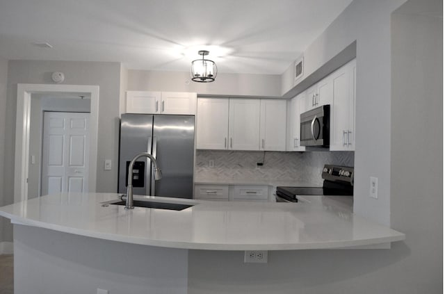 kitchen with tasteful backsplash, stainless steel appliances, kitchen peninsula, and white cabinets