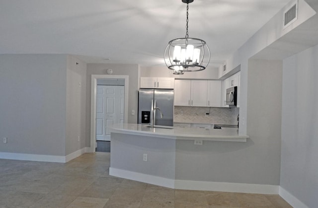 kitchen with white cabinetry, hanging light fixtures, backsplash, stainless steel appliances, and kitchen peninsula