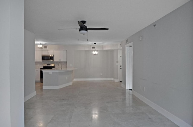 unfurnished living room featuring sink and ceiling fan with notable chandelier