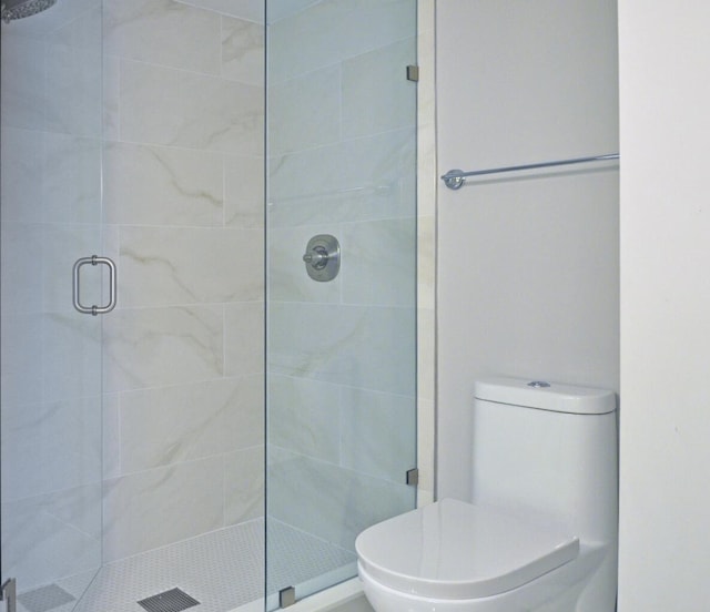 bathroom featuring toilet and a shower with door