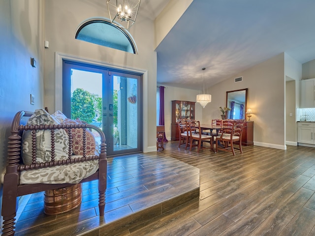 foyer entrance featuring an inviting chandelier, high vaulted ceiling, dark hardwood / wood-style floors, and french doors