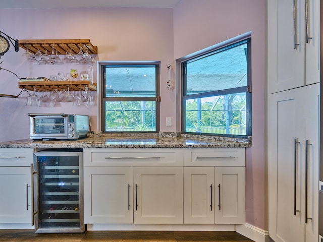 bar featuring wine cooler, white cabinetry, and stone countertops