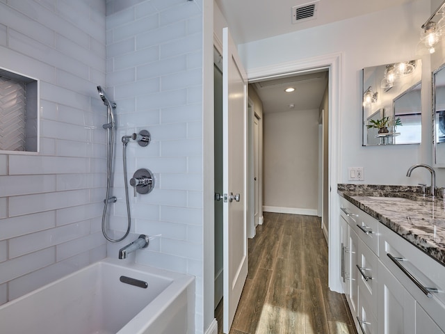 bathroom with vanity, tiled shower / bath combo, and wood-type flooring