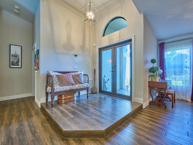 foyer entrance featuring dark wood-type flooring, high vaulted ceiling, french doors, and a chandelier