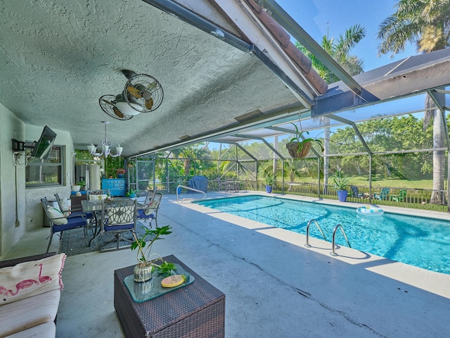 view of swimming pool with ceiling fan, a lanai, and a patio